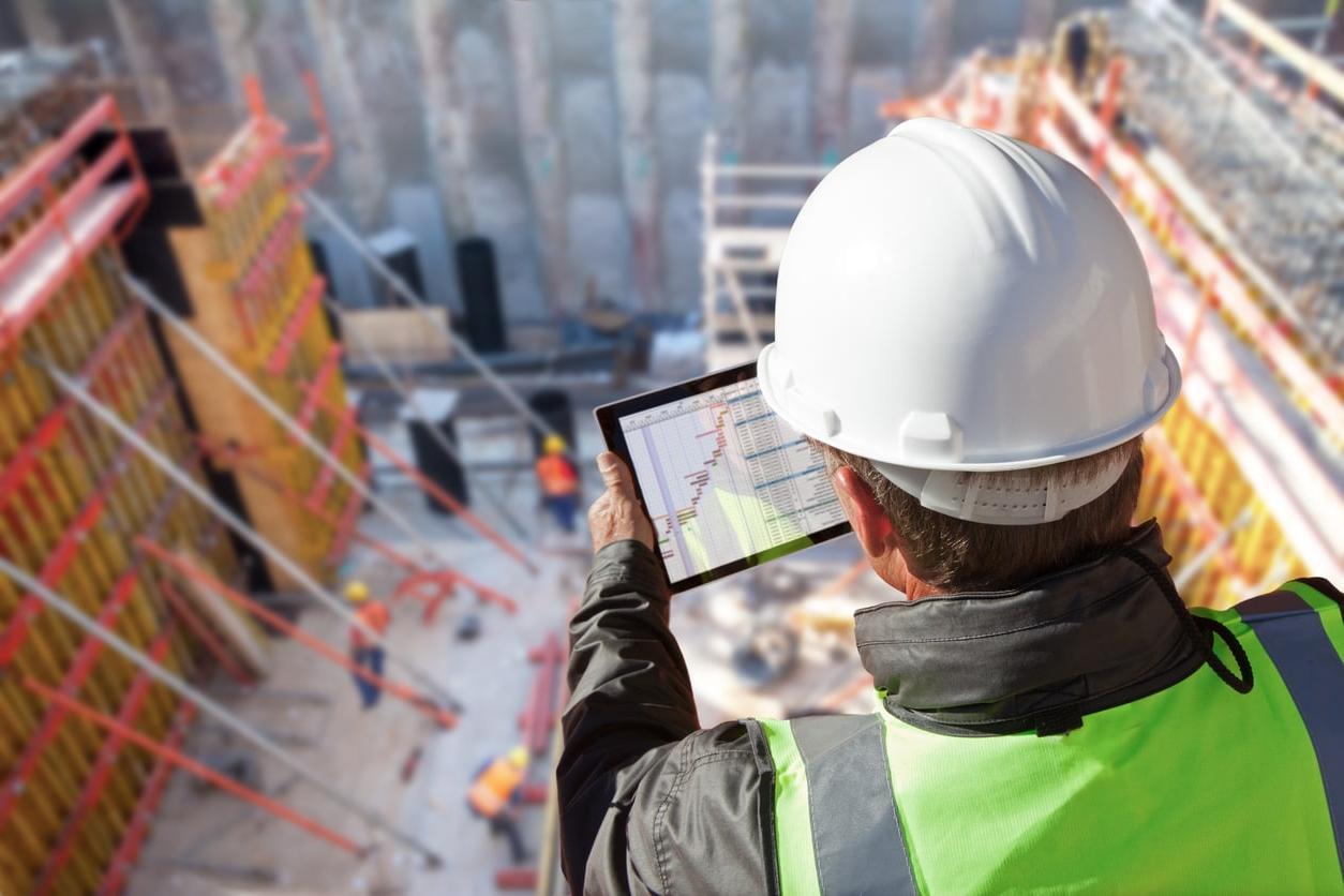 An engineer with a tablet looks down on a multi-level 商业建筑 site.